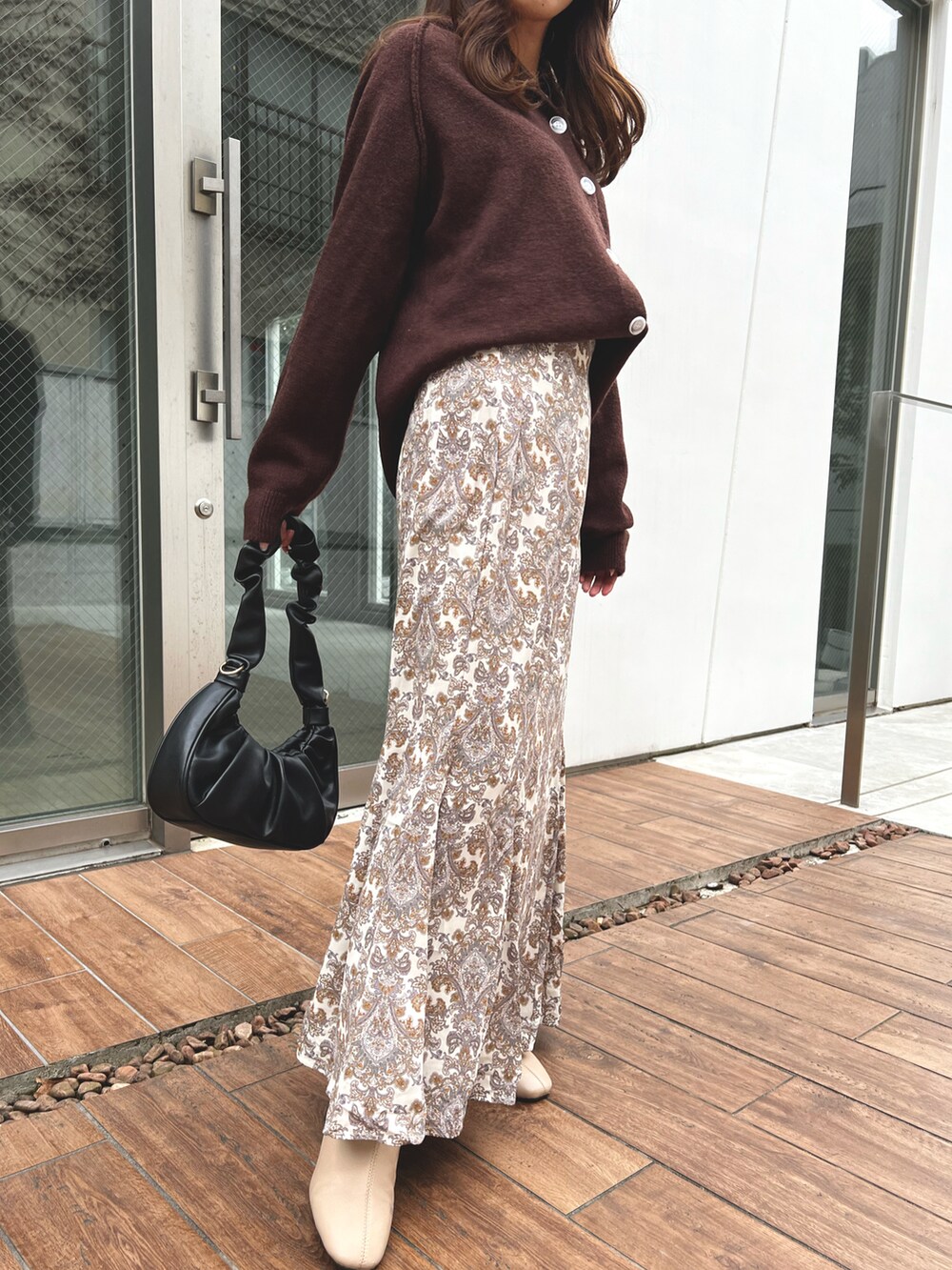 ブラウン系のニット/セーター、ホワイト系のスカートを着用したレディースの冬コーディネートの2枚目の写真