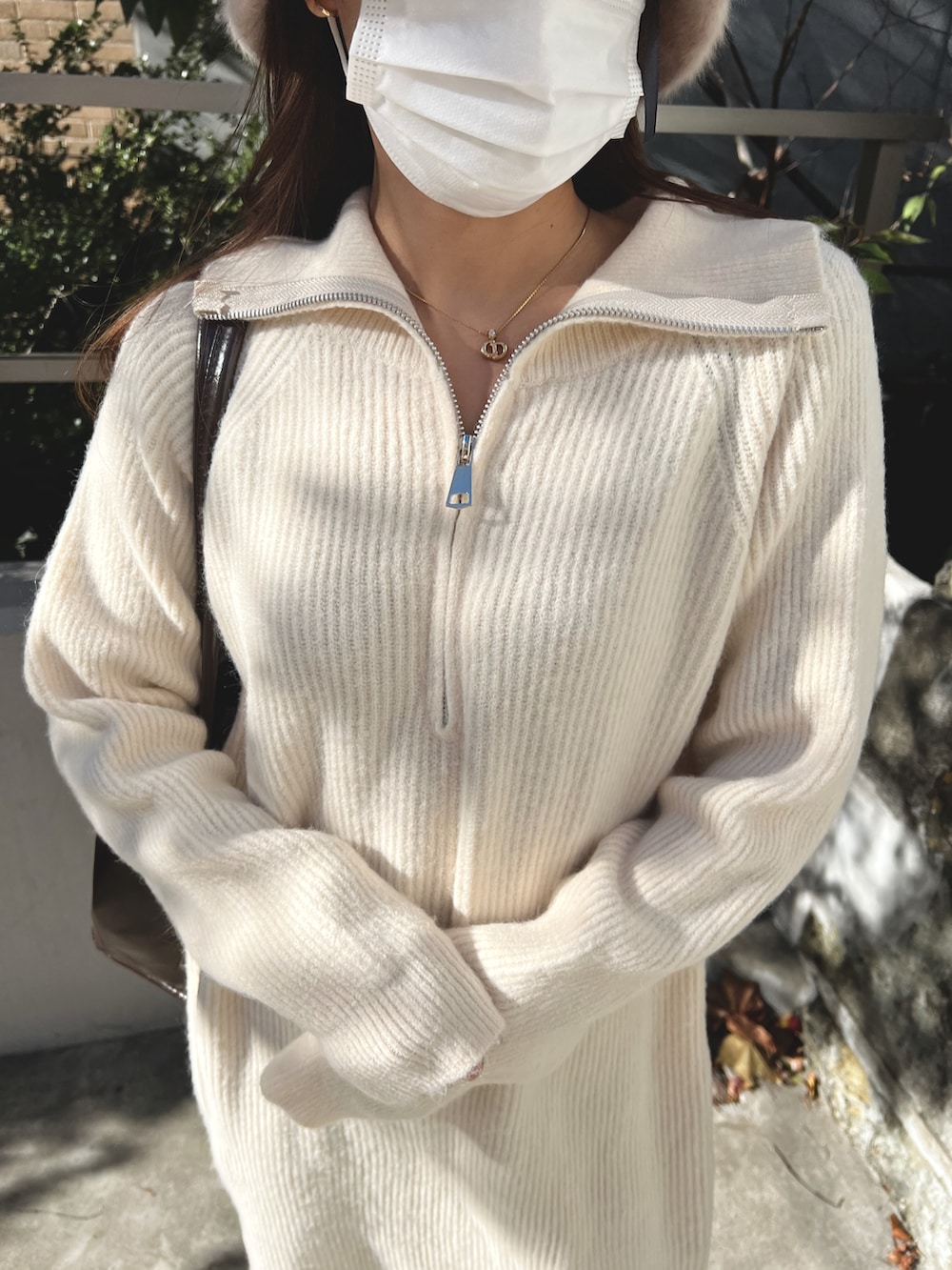 ホワイト系のワンピース、ブラウン系のブーツ、ブラウン系のトートバッグを着用したレディースの冬コーディネートの3枚目の写真