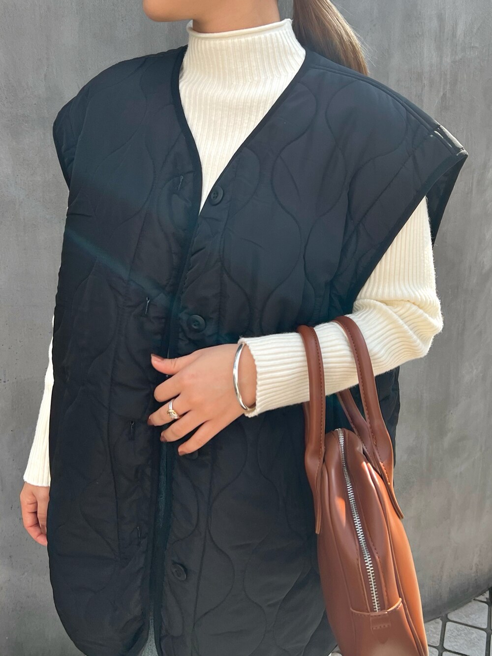 ブラウン系のボストンバッグ、ブラック系のノーカラージャケットを着用したレディースの春コーディネートの2枚目の写真