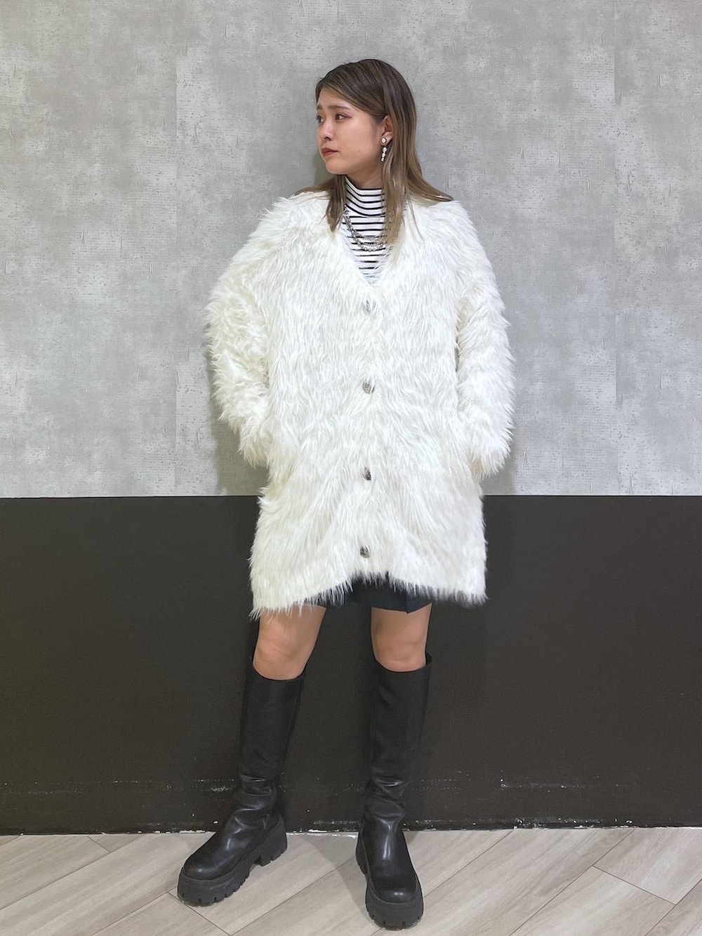 ホワイト系のカーディガン/ボレロ、ブラック系のブーツ、ブラック系のスカートを着用したレディースの秋コーディネートの4枚目の写真