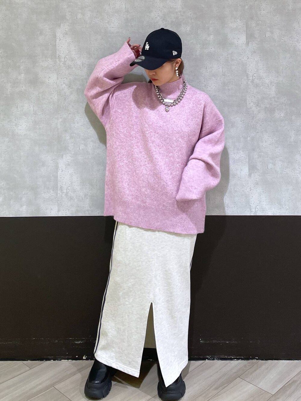 ブラック系のブーツ、レッド系のニット/セーター、ベージュ系のスカートを着用したレディースの秋コーディネートの4枚目の写真