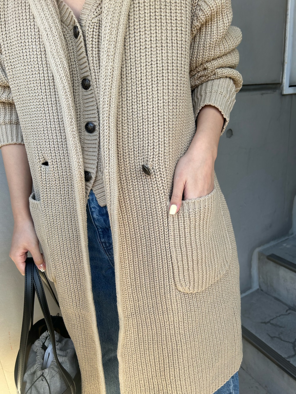 ベージュ系のベスト、ブルー系のチェスターコート、ブルー系のデニムパンツを着用したレディースの冬コーディネートの3枚目の写真