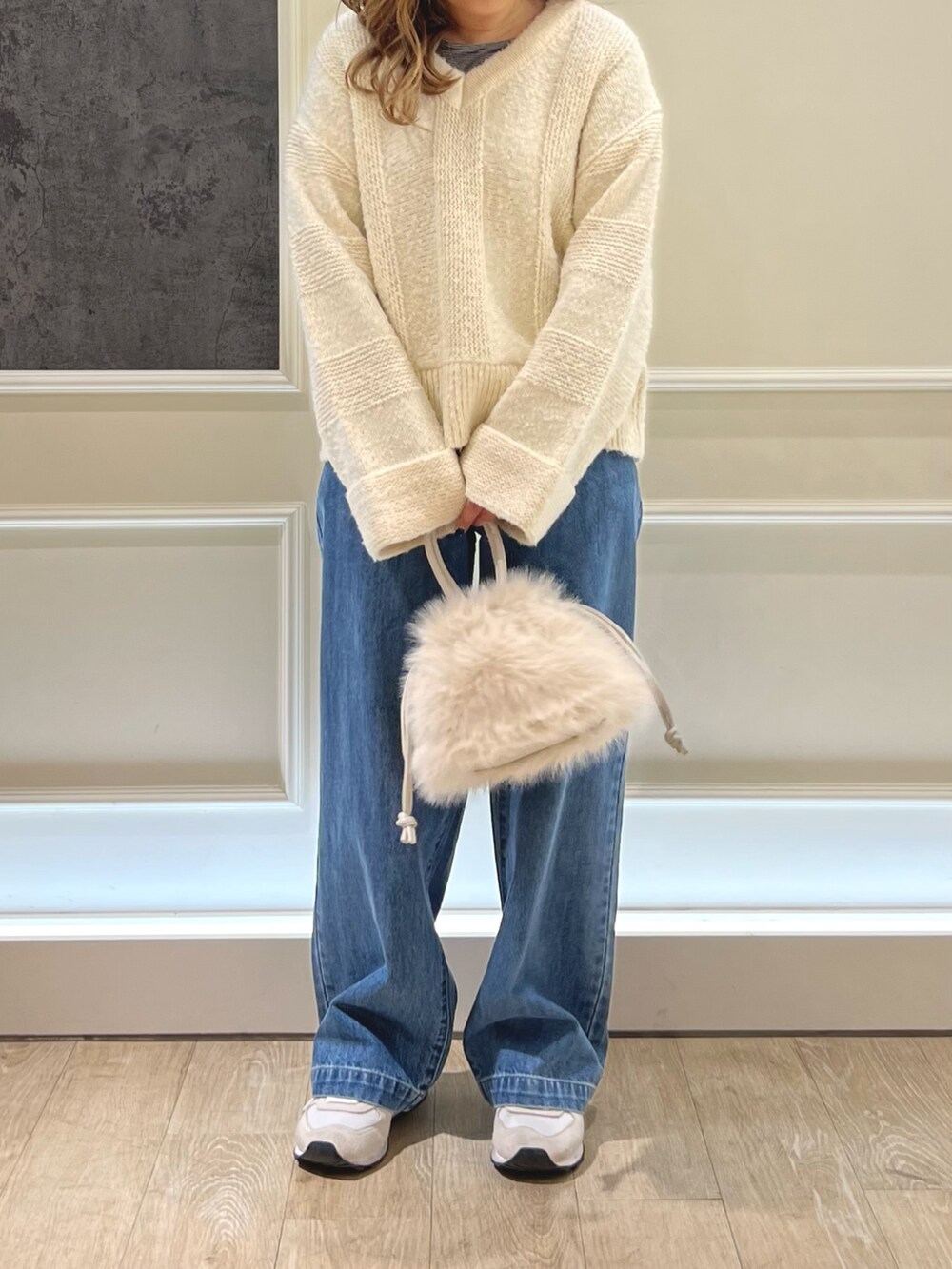 ホワイト系のニット/セーター、ブラック系のTシャツ/カットソー、ベージュ系のハンドバッグを着用したレディースの冬コーディネートの2枚目の写真