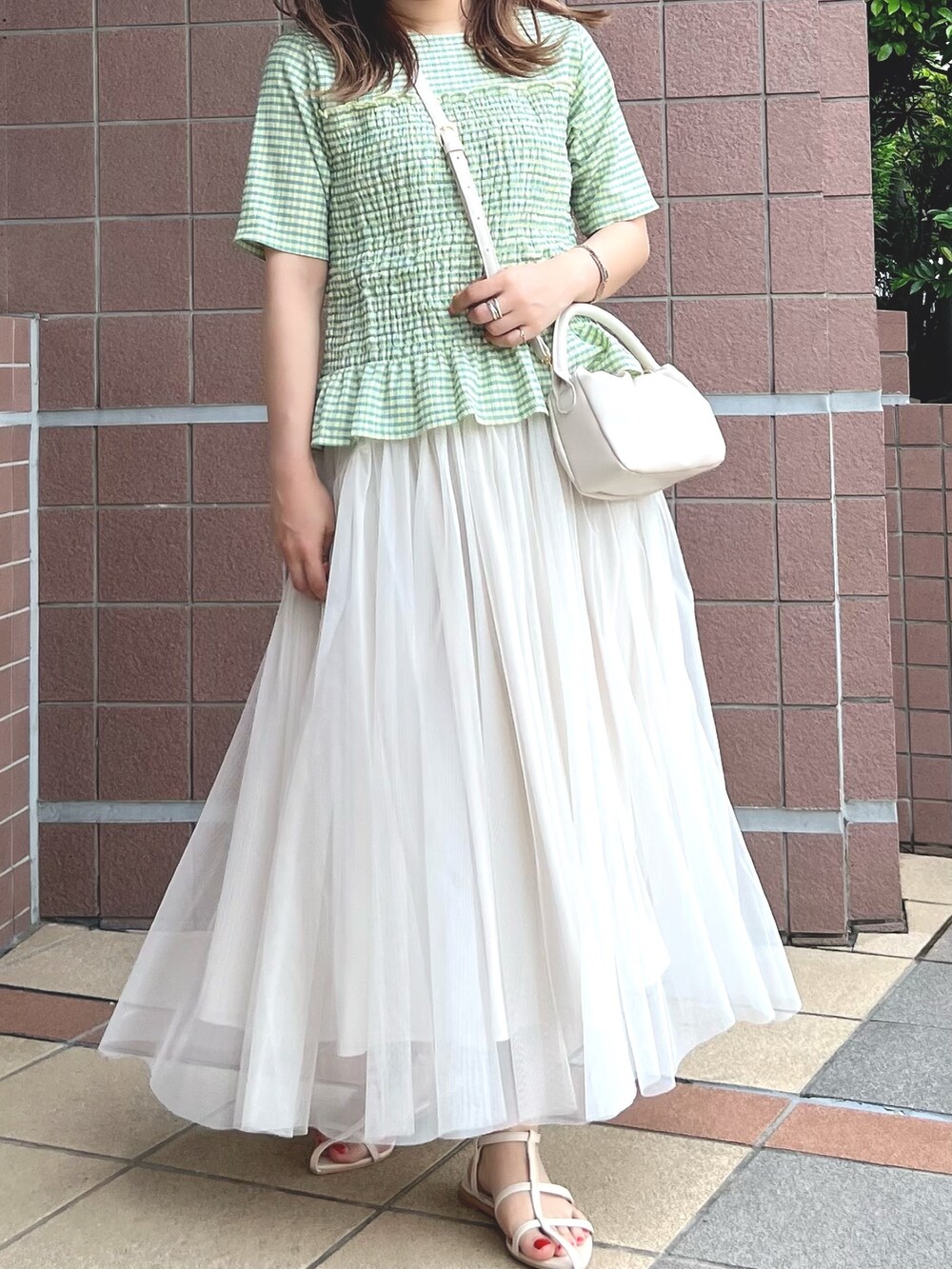 ホワイト系のサンダル、ホワイト系のスカート、ホワイト系のトートバッグを着用したレディースの夏コーディネートの2枚目の写真