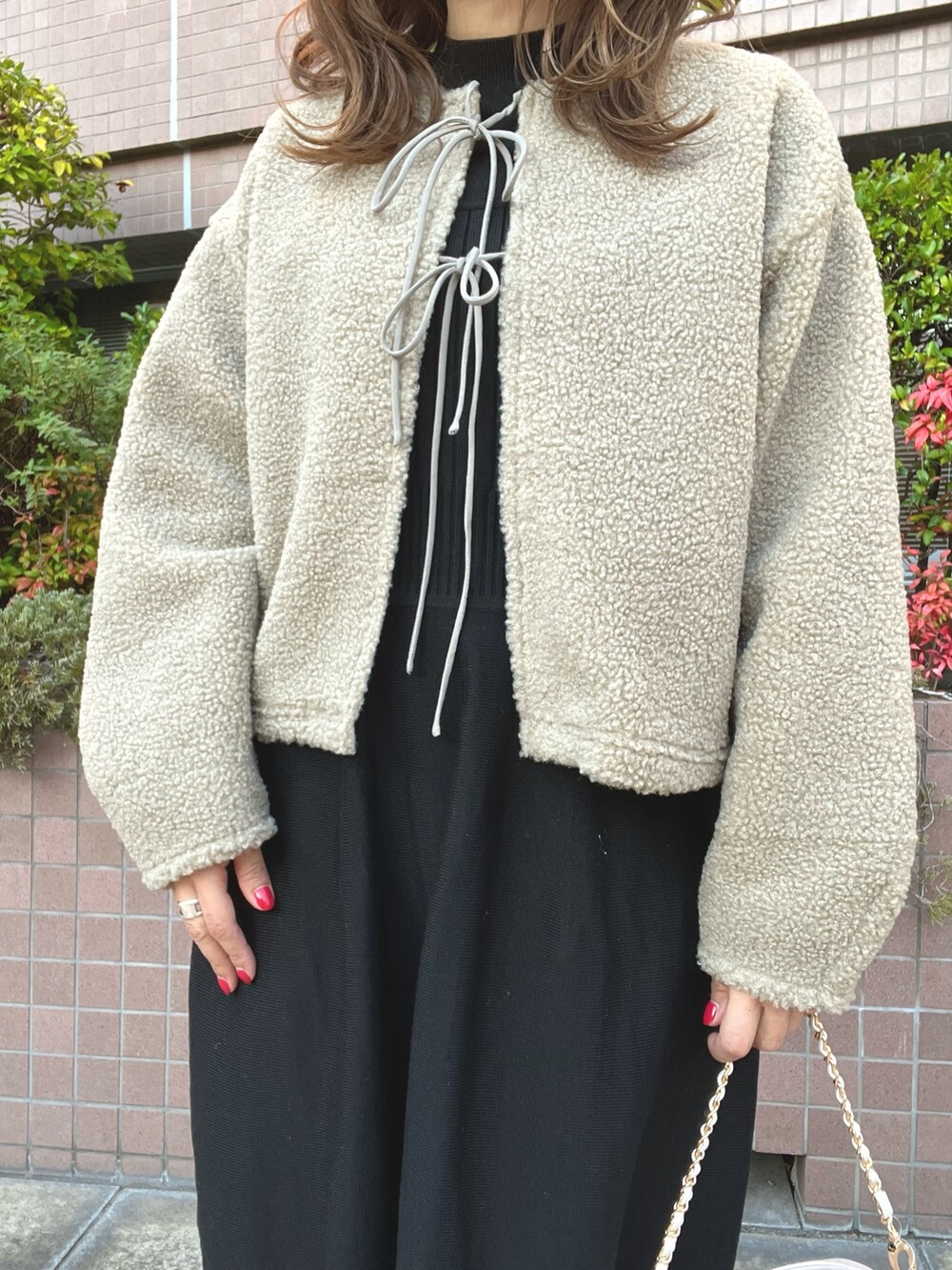 ブラック系のワンピース、ベージュ系のカーディガン/ボレロ、ベージュ系のショルダーバッグを着用したレディースの秋コーディネートの2枚目の写真