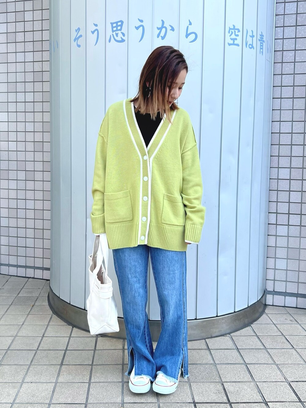 グリーン系のカーディガン/ボレロ、ブルー系のデニムパンツ、ホワイト系のトートバッグを着用したレディースの冬コーディネートの2枚目の写真