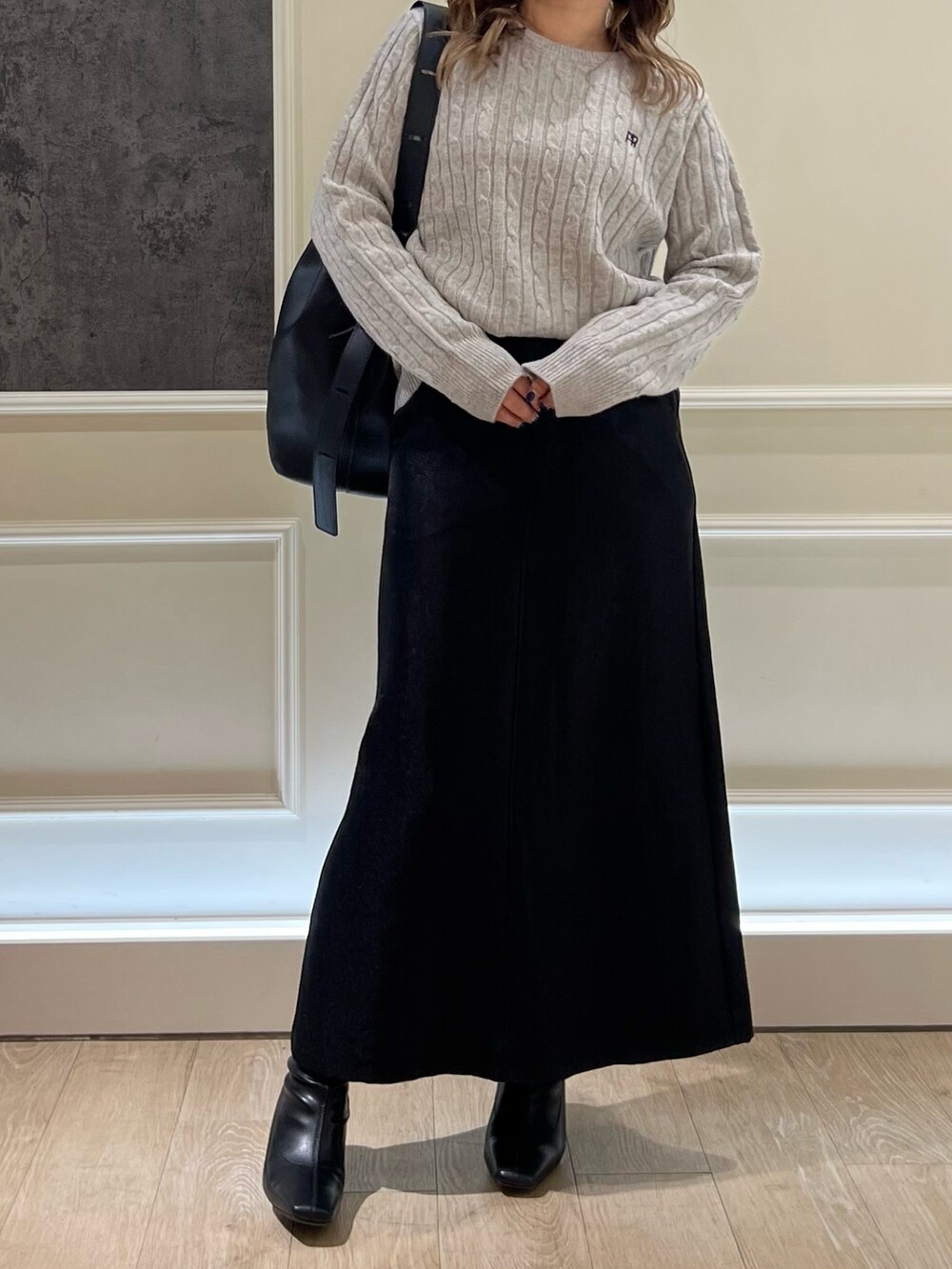 ブラック系のスカート、グレー系のニット/セーター、ブラック系のハンドバッグを着用したレディースの秋コーディネートの3枚目の写真