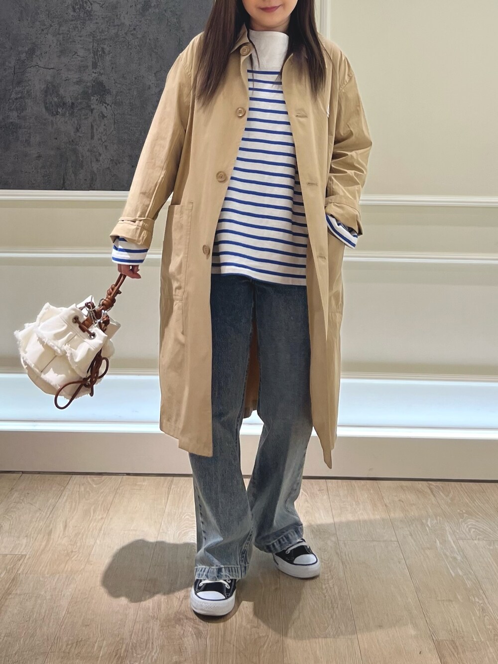 ベージュ系のステンカラーコート、ブルー系のTシャツ/カットソー、ブルー系のデニムパンツを着用したレディースの春コーディネートの2枚目の写真