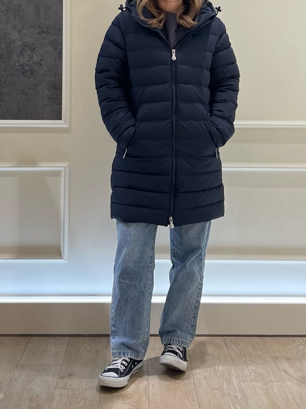 ブルー系のデニムパンツ、ブルー系のダウンジャケット/コート、ブラック系のスニーカーを着用したレディースの秋コーディネートの3枚目の写真