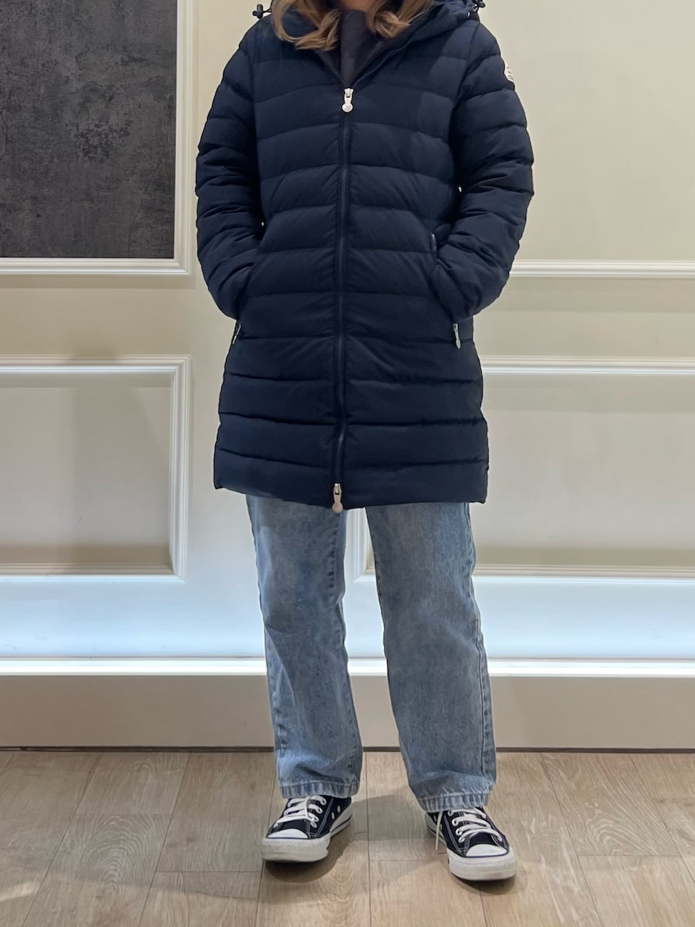 ブルー系のデニムパンツ、ブルー系のダウンジャケット/コート、ブラック系のスニーカーを着用したレディースの秋コーディネートの2枚目の写真