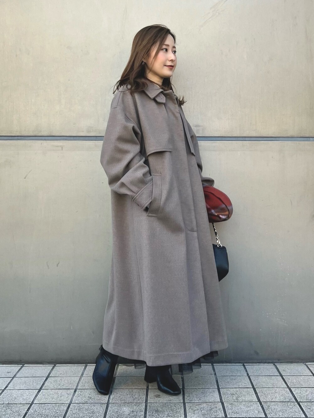 ブラウン系のステンカラーコート、ブラック系のショルダーバッグ、ホワイト系のニット/セーターを着用したレディースの秋コーディネートの2枚目の写真