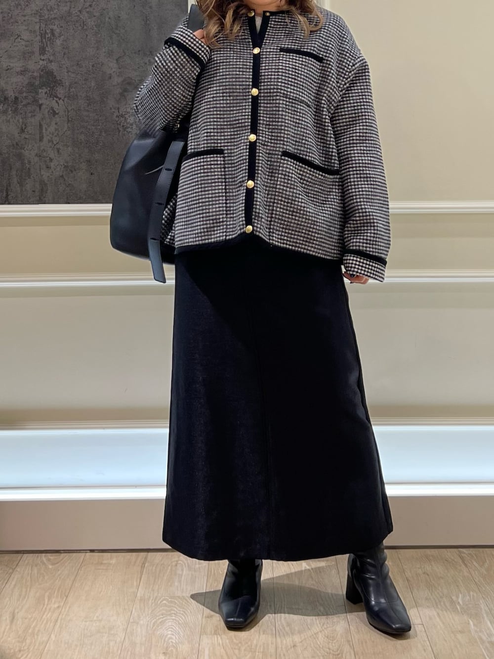 ブラック系のブルゾン、ブラック系のハンドバッグ、ブラック系のスカートを着用したレディースの秋コーディネートの2枚目の写真