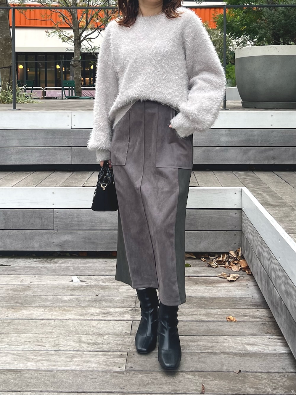 グレー系のスカート、グレー系のニット/セーターを着用したレディースの秋コーディネートの2枚目の写真