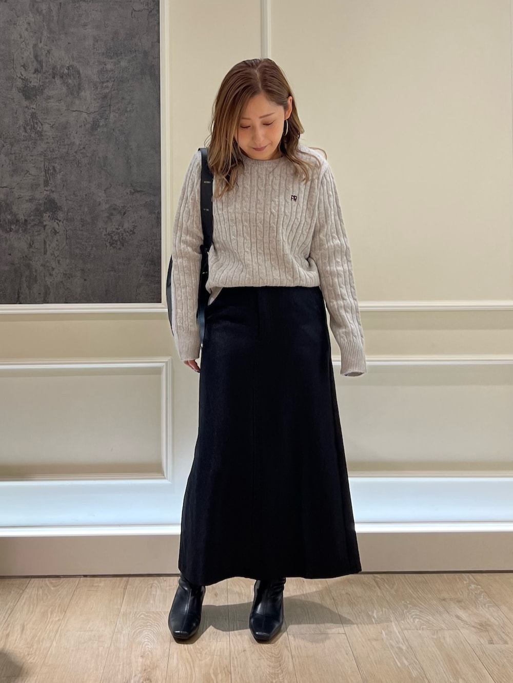 ブラック系のスカート、グレー系のニット/セーター、ブラック系のハンドバッグを着用したレディースの秋コーディネートの2枚目の写真