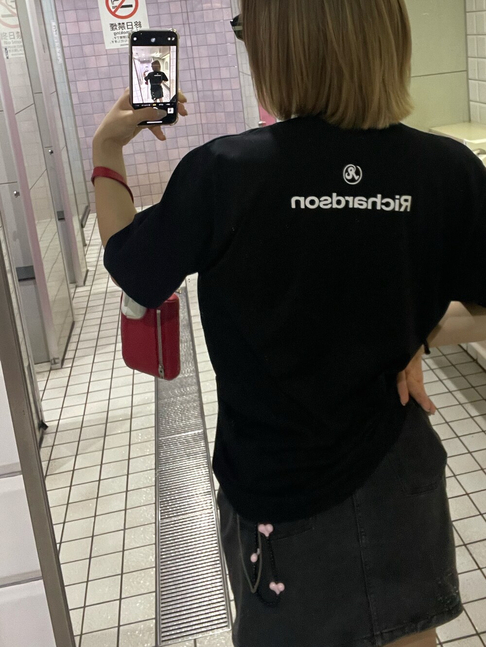 レッド系のクラッチバッグ、ブラック系のTシャツ/カットソーを着用したレディースの夏コーディネートの2枚目の写真