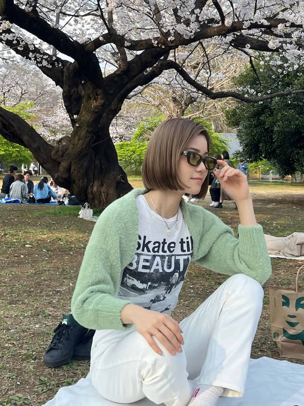 グリーン系のスニーカー、ホワイト系のデニムパンツを着用したレディースの春コーディネートの3枚目の写真