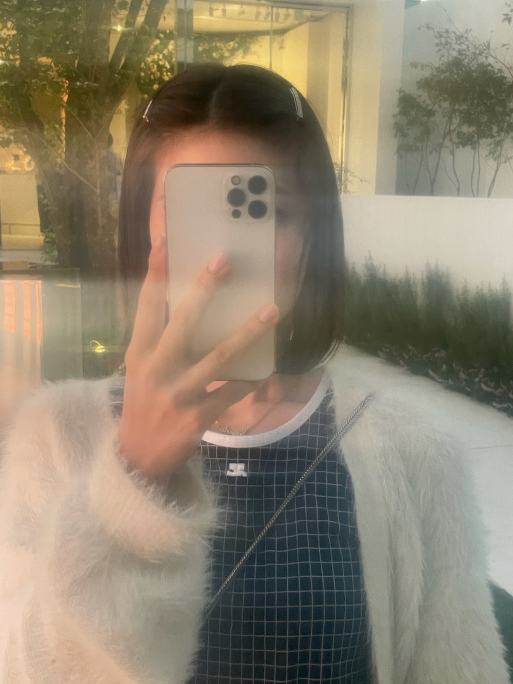 シルバー系のハンドバッグ、ホワイト系のデニムパンツ、ブルー系のタンクトップを着用したレディースの秋コーディネートの2枚目の写真