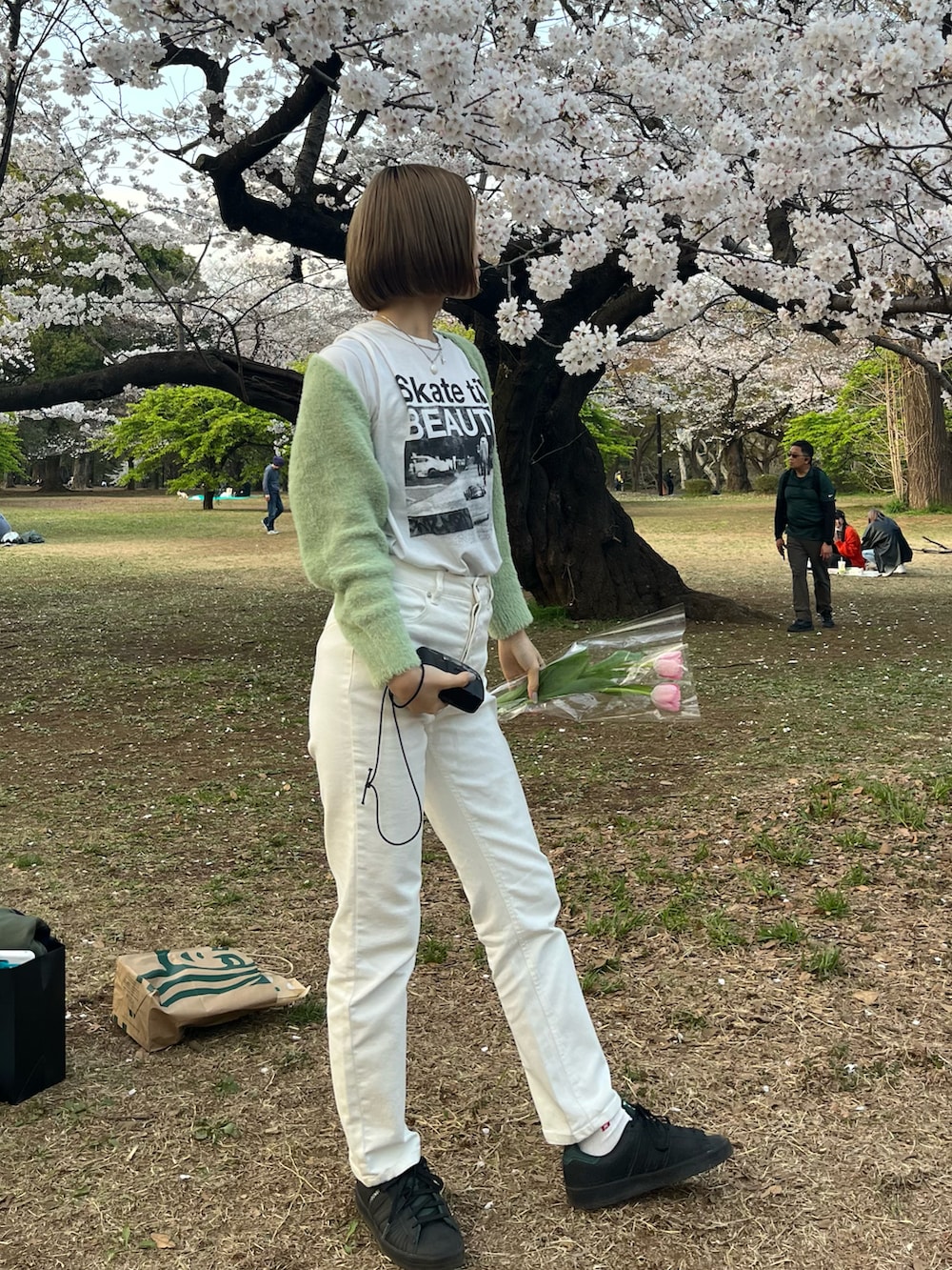 グリーン系のスニーカー、ホワイト系のデニムパンツを着用したレディースの春コーディネートの2枚目の写真