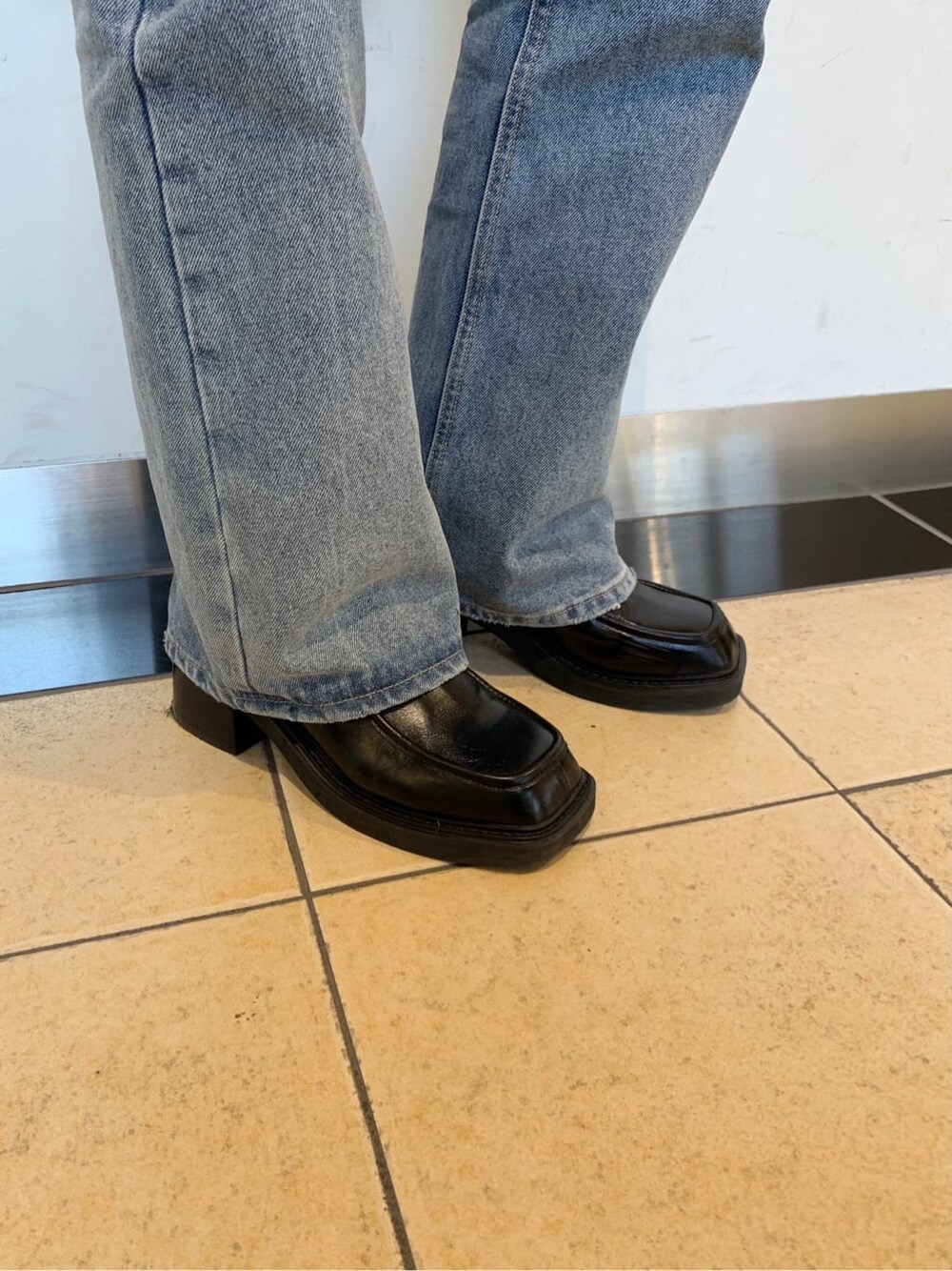 ブラック系のブーツ、ブルー系のデニムパンツ、グレー系のチェスターコートを着用したレディースの秋コーディネートの7枚目の写真