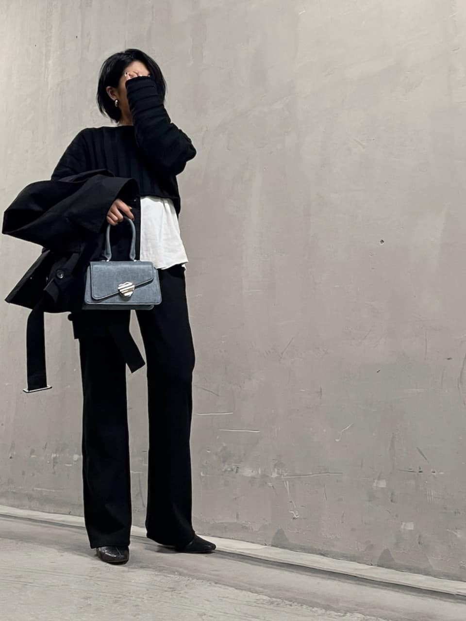 ブラック系のトレンチコート、ブラック系のその他パンツ、ブルー系のハンドバッグを着用したレディースの冬コーディネートの3枚目の写真
