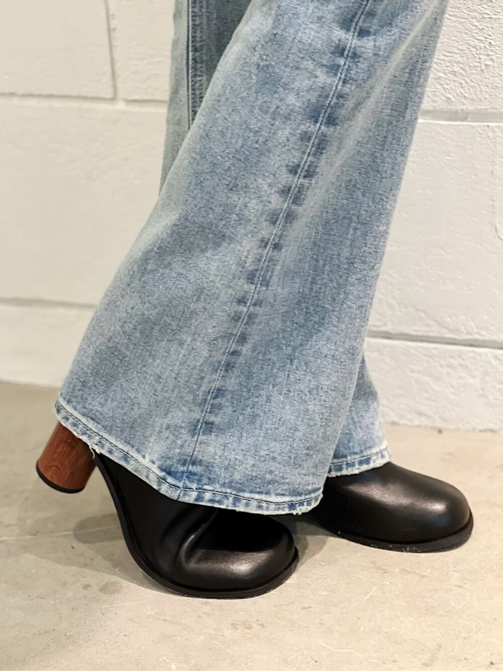 ブラック系のベスト、ブラック系のブーツ、ブルー系のデニムパンツを着用したレディースの春コーディネートの6枚目の写真