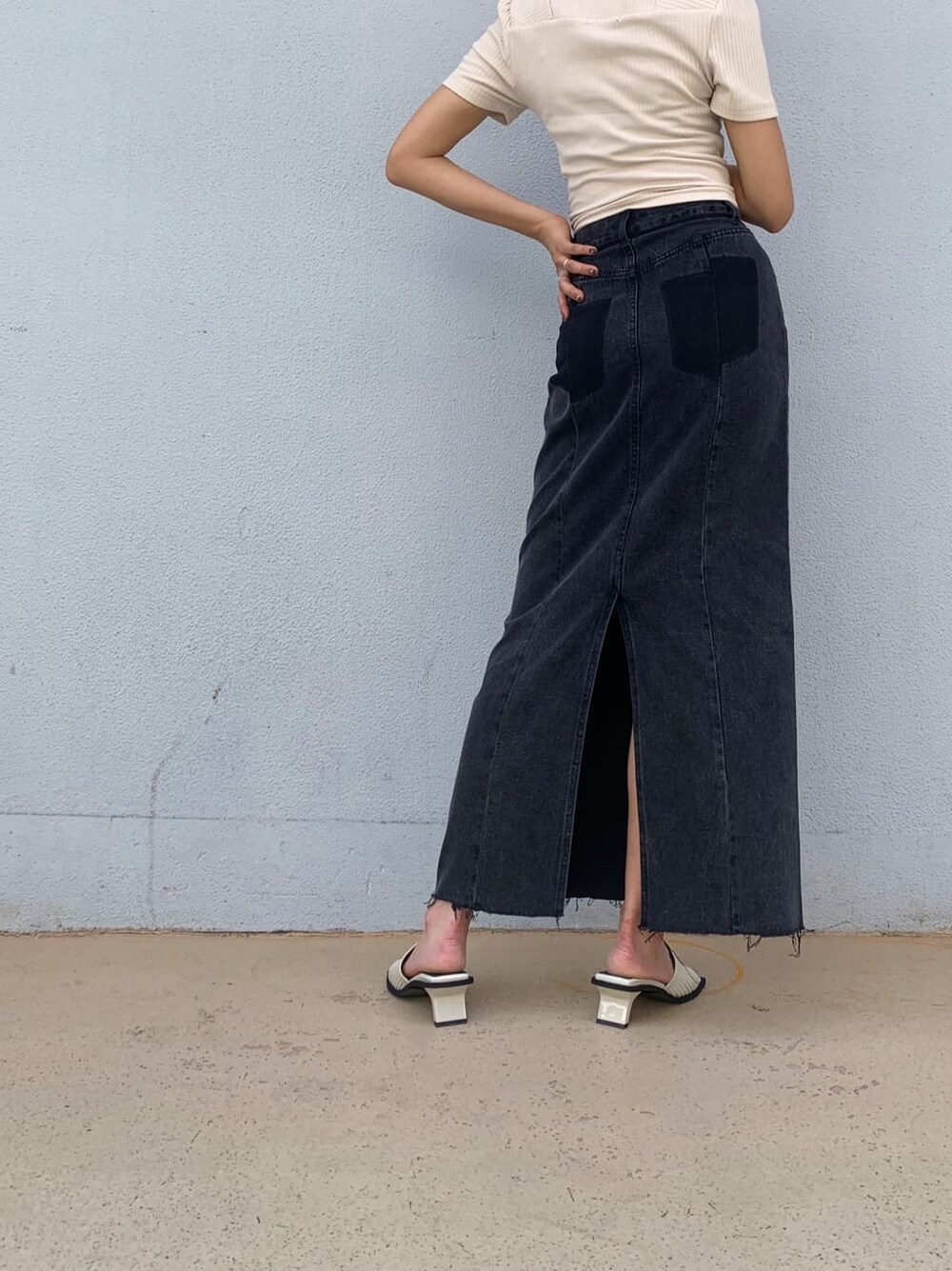 ブラック系のデニムスカート、ホワイト系のサンダル、ホワイト系のTシャツ/カットソーを着用したレディースの夏コーディネートの5枚目の写真