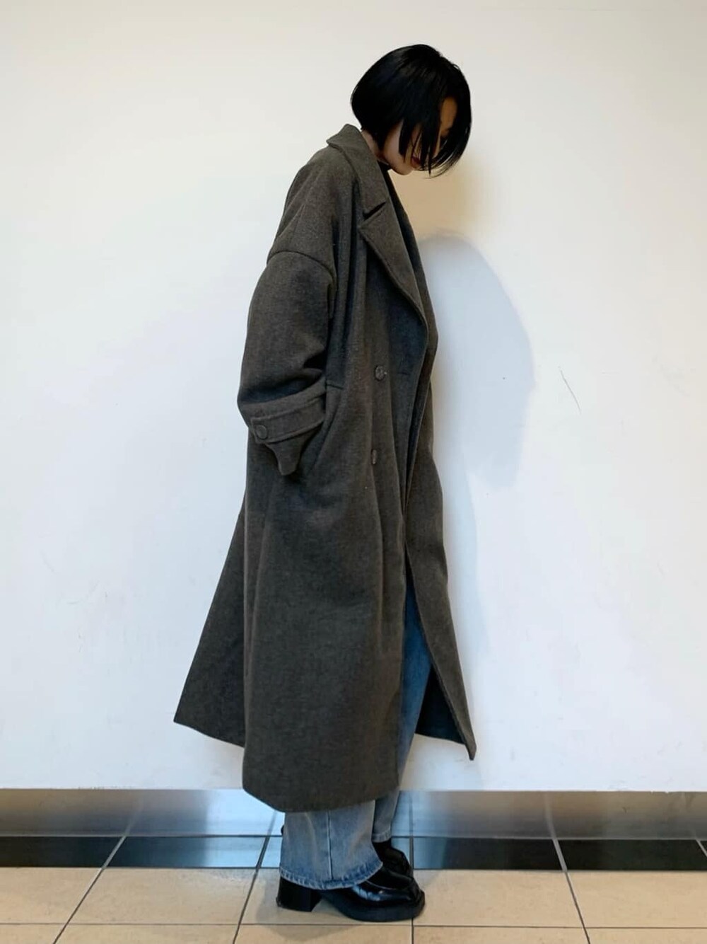 ブラック系のブーツ、ブルー系のデニムパンツ、グレー系のチェスターコートを着用したレディースの秋コーディネートの3枚目の写真