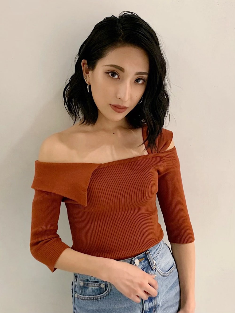 ブルー系のデニムパンツ、オレンジ系のニット/セーターを着用したレディースの春コーディネートの2枚目の写真