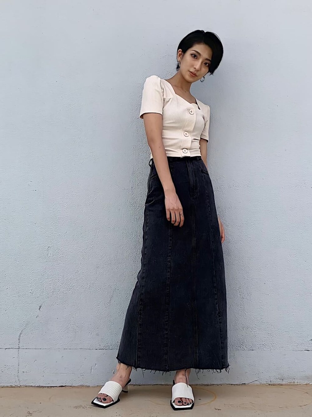 ブラック系のデニムスカート、ホワイト系のサンダル、ホワイト系のTシャツ/カットソーを着用したレディースの夏コーディネートの2枚目の写真