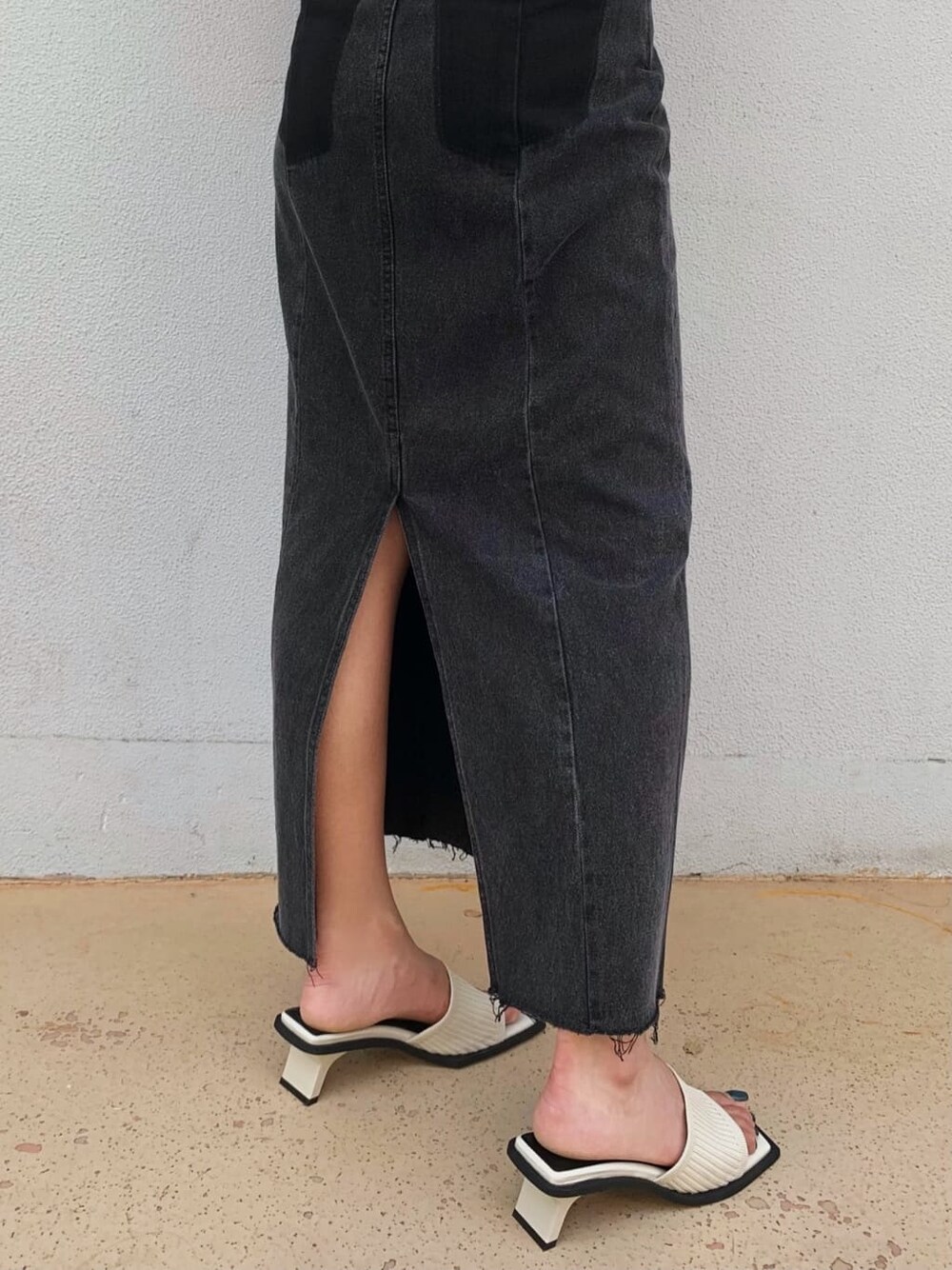 ブラック系のデニムスカート、ホワイト系のサンダル、ホワイト系のTシャツ/カットソーを着用したレディースの夏コーディネートの6枚目の写真