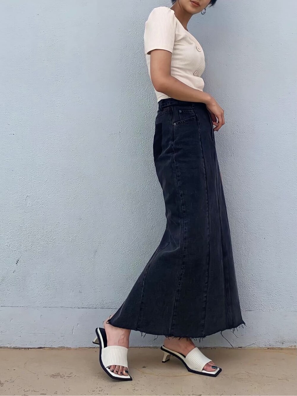 ブラック系のデニムスカート、ホワイト系のサンダル、ホワイト系のTシャツ/カットソーを着用したレディースの夏コーディネートの3枚目の写真