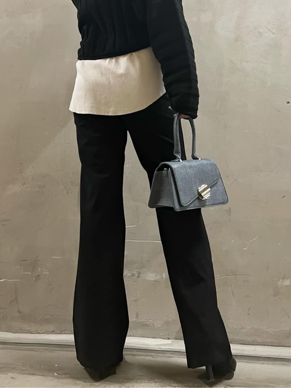 ブラック系のトレンチコート、ブラック系のその他パンツ、ブルー系のハンドバッグを着用したレディースの冬コーディネートの4枚目の写真