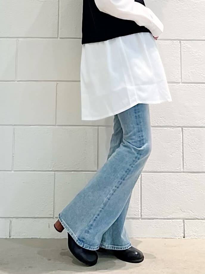 ブラック系のベスト、ブラック系のブーツ、ブルー系のデニムパンツを着用したレディースの春コーディネートの4枚目の写真