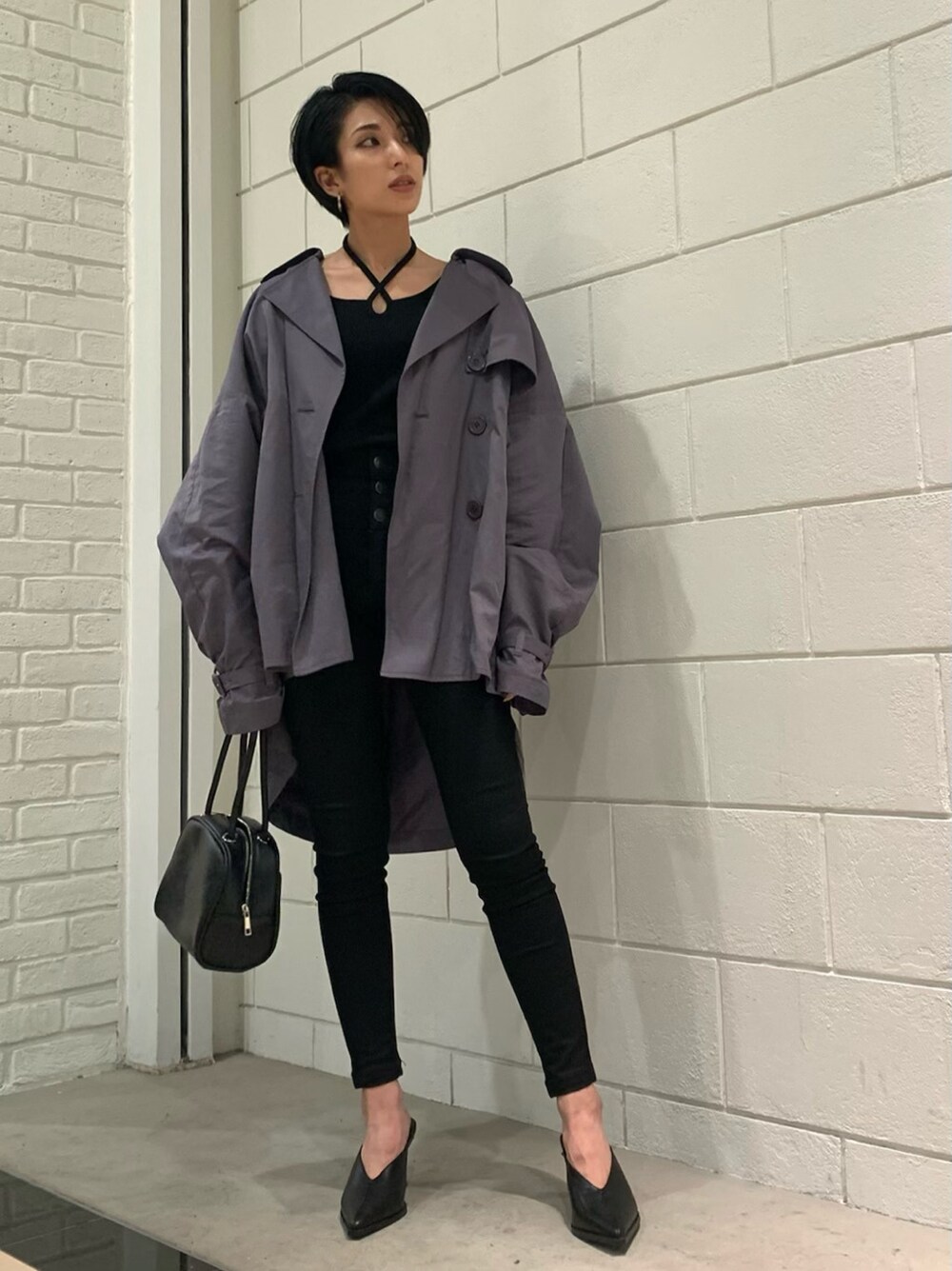 パープル系のトレンチコート、ブラック系のハンドバッグ、ブラック系のサンダルを着用したレディースの春コーディネートの2枚目の写真