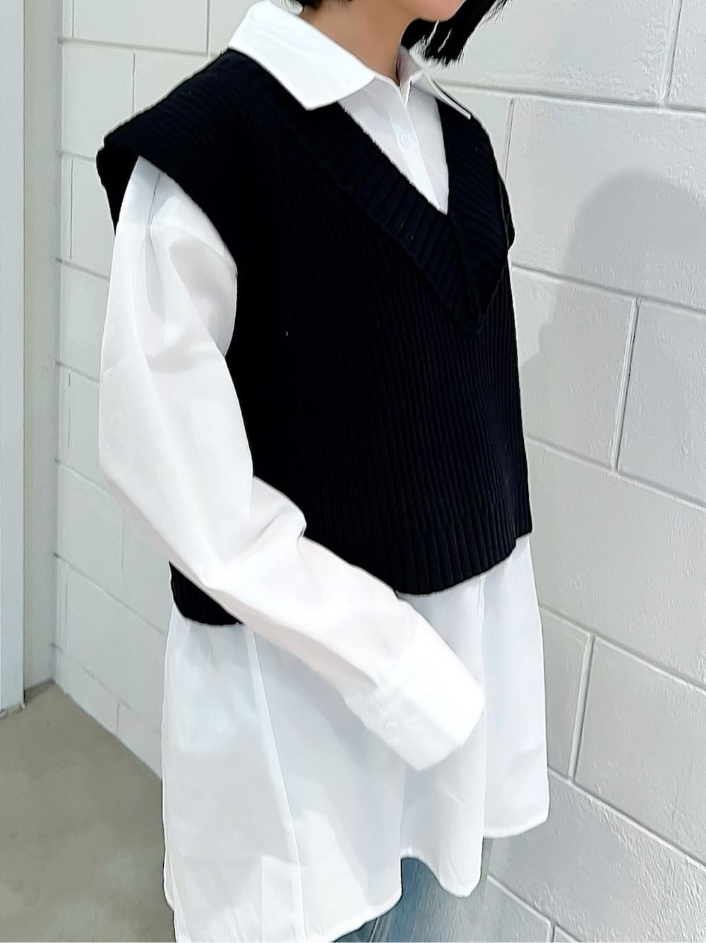 ブラック系のベスト、ブラック系のブーツ、ブルー系のデニムパンツを着用したレディースの春コーディネートの5枚目の写真