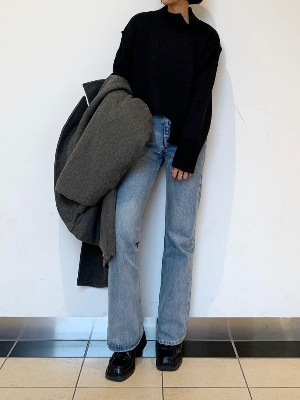 ブラック系のブーツ、ブルー系のデニムパンツ、グレー系のチェスターコートを着用したレディースの秋コーディネートの5枚目の写真