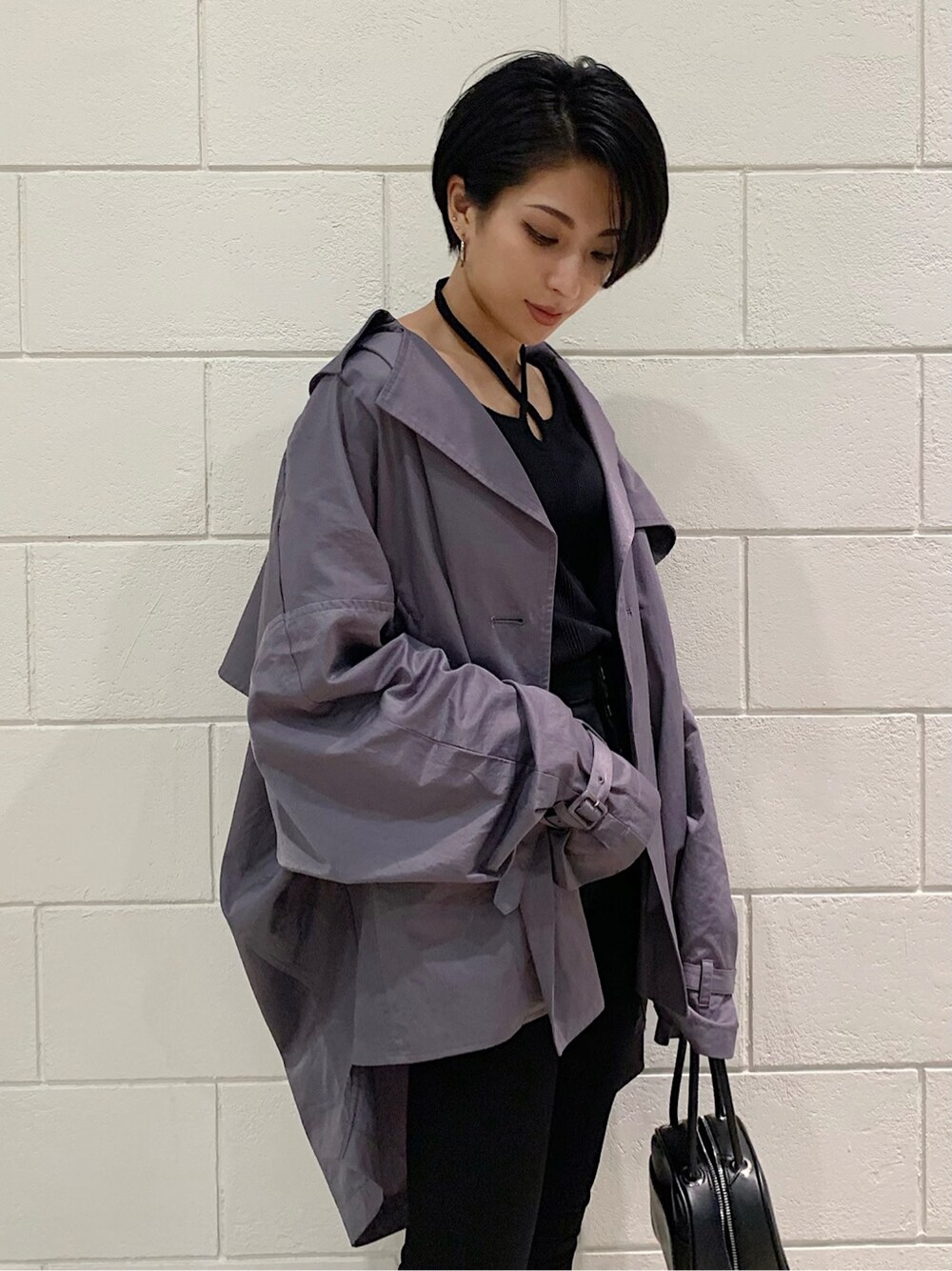 パープル系のトレンチコート、ブラック系のハンドバッグ、ブラック系のサンダルを着用したレディースの春コーディネートの3枚目の写真