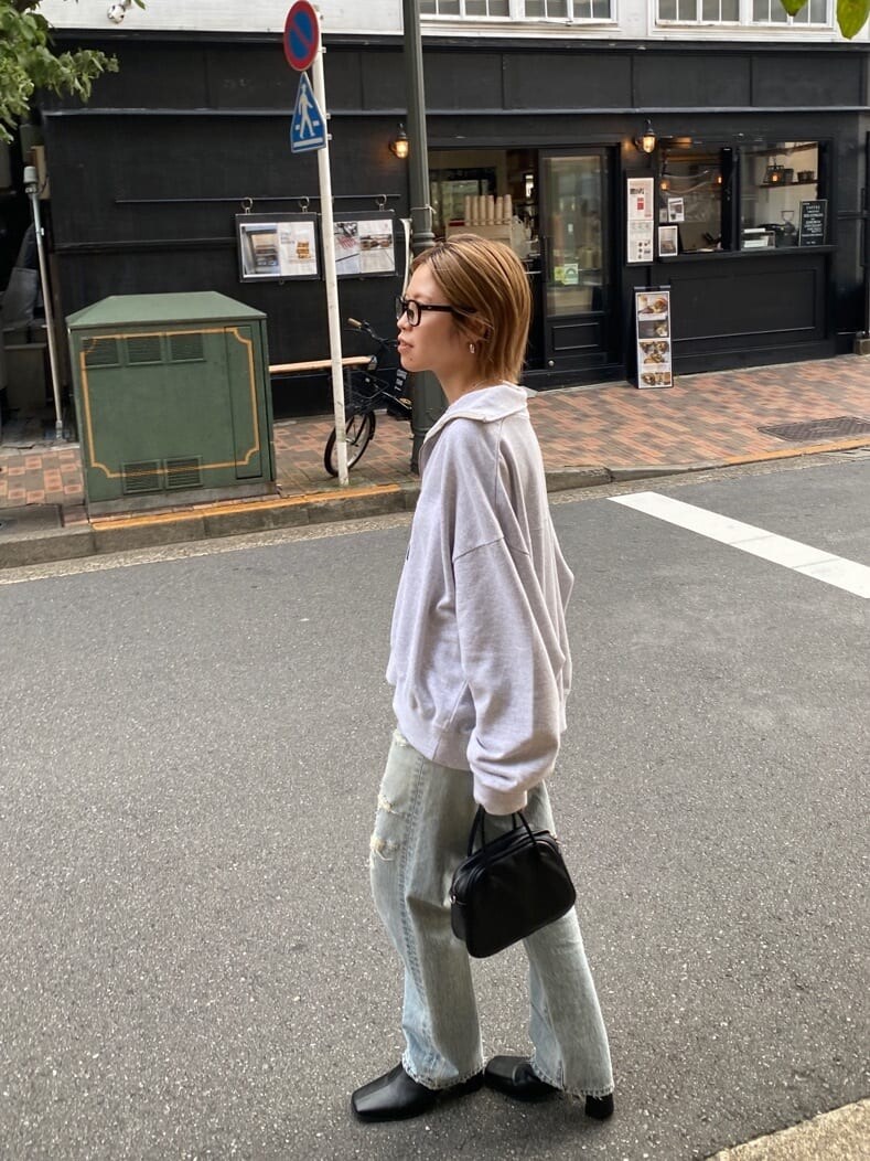 グレー系のスウェット、ブラック系のブーツ、ブルー系のデニムパンツを着用したレディースの春コーディネートの2枚目の写真