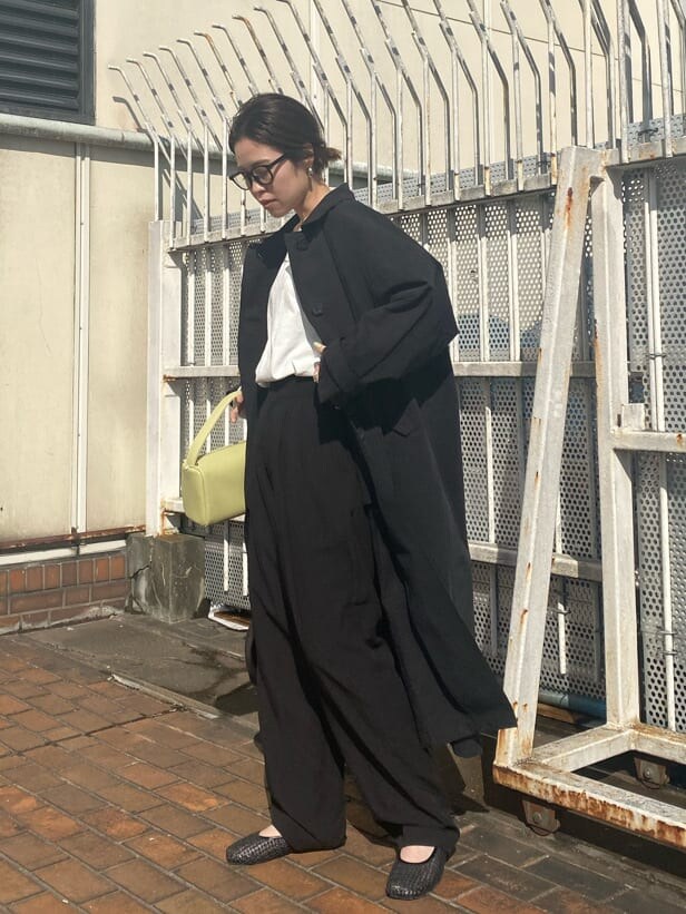 ブラック系のパンプス、ブラック系のステンカラーコート、ブラック系のスラックスを着用したレディースの冬コーディネートの2枚目の写真