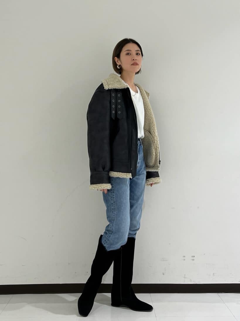 ブラック系のブルゾン、ブラック系のブーツ、ブルー系のデニムパンツを着用したレディースの秋コーディネートの2枚目の写真