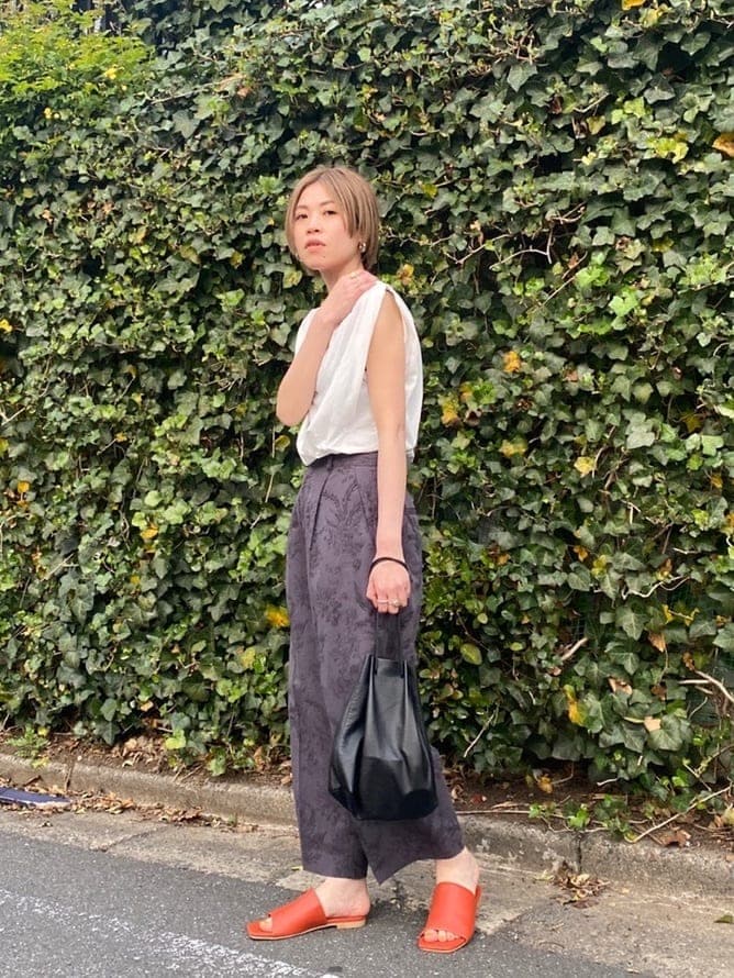 グレー系のその他パンツ、オレンジ系のサンダルを着用したレディースの春コーディネートの3枚目の写真