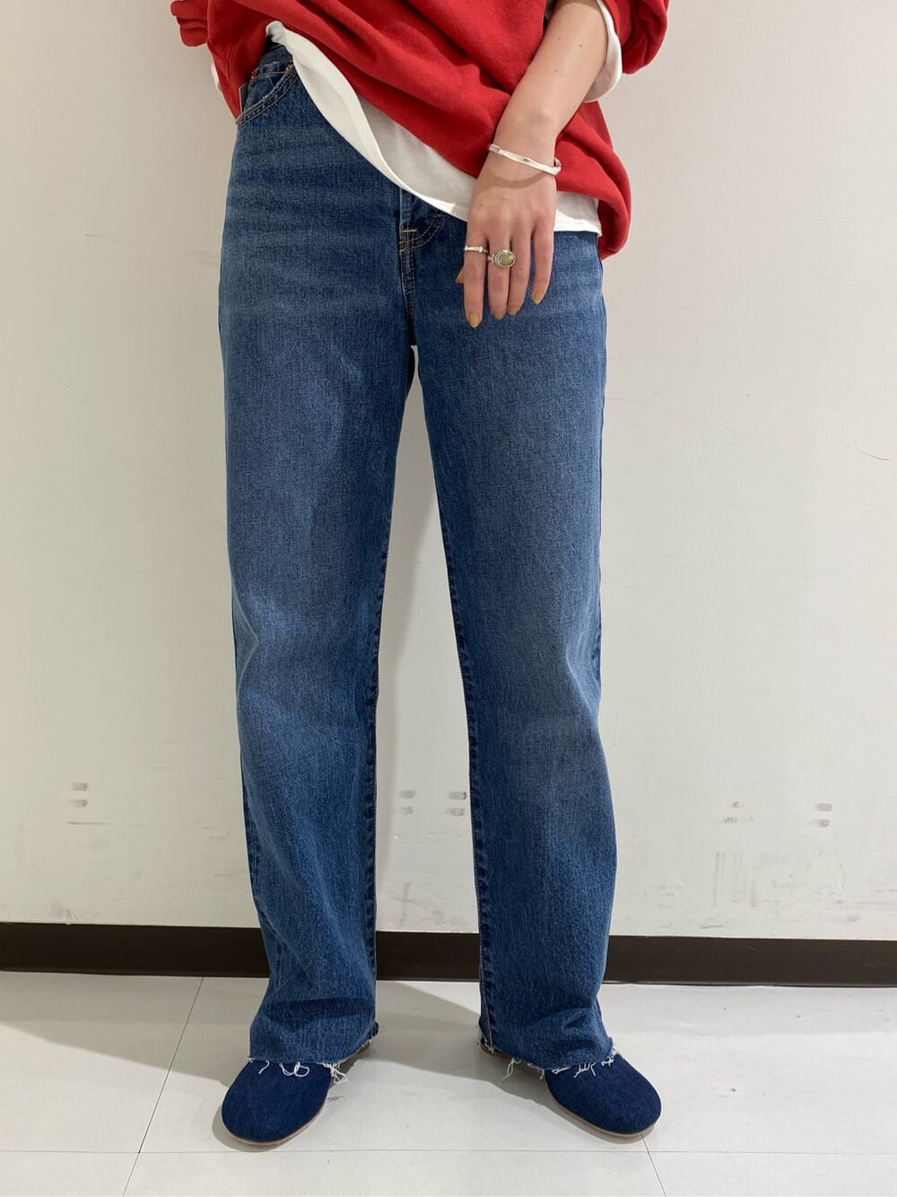 ブルー系のデニムパンツ、ホワイト系のTシャツ/カットソー、レッド系のスウェットを着用したレディースの秋コーディネートの2枚目の写真