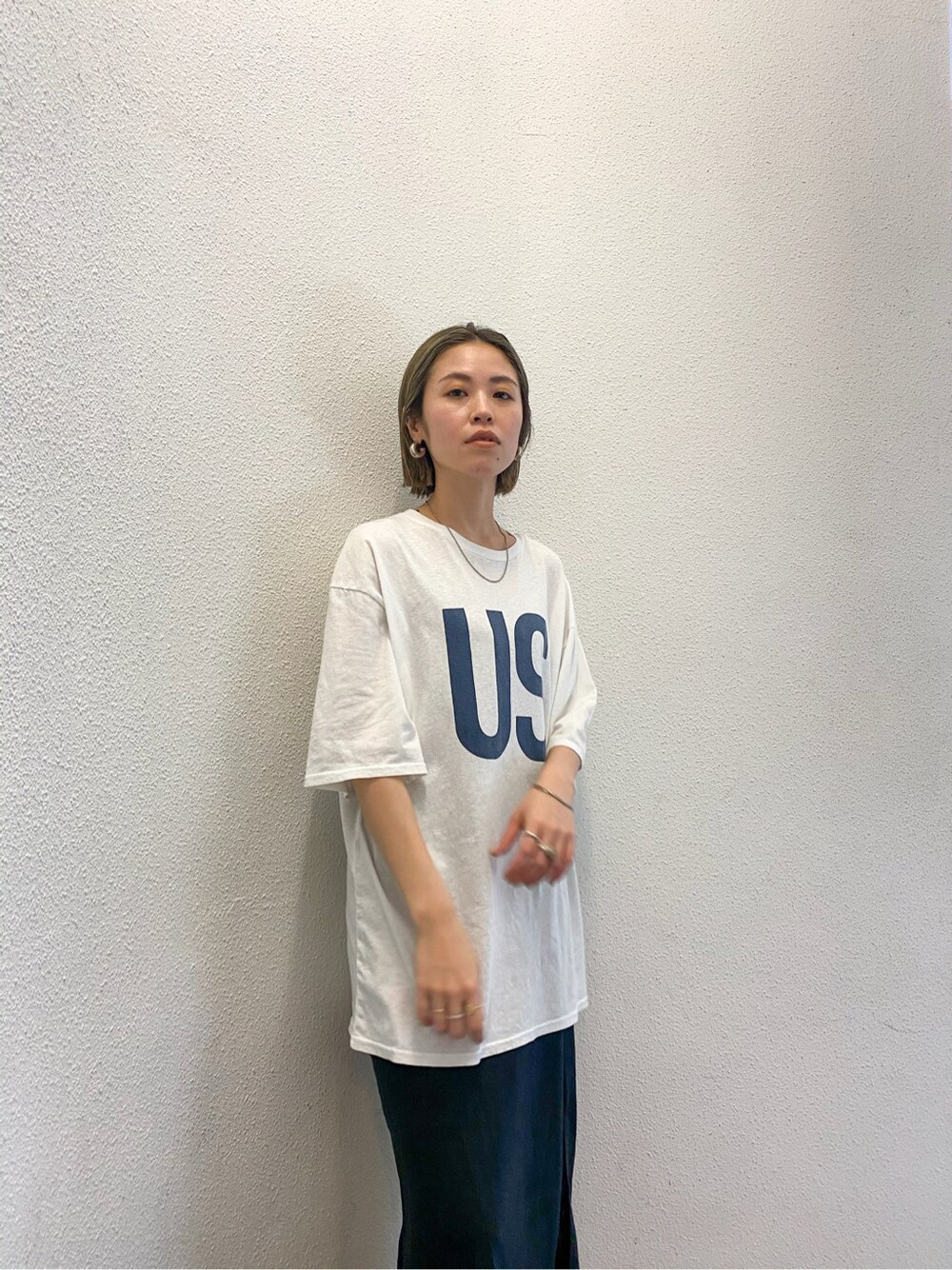 ブラック系のスカート、ブラック系のサンダル、ホワイト系のTシャツ/カットソーを着用したレディースの春コーディネートの2枚目の写真
