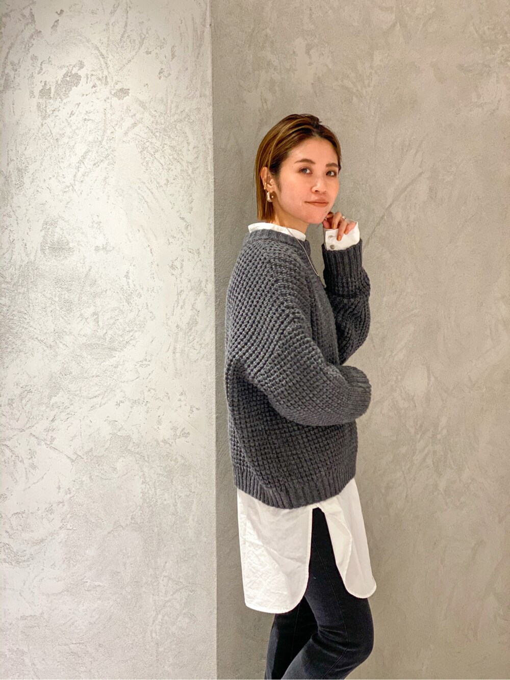 ブラック系のデニムパンツ、ブラック系のブーツ、グレー系のニット/セーターを着用したレディースの秋コーディネートの2枚目の写真