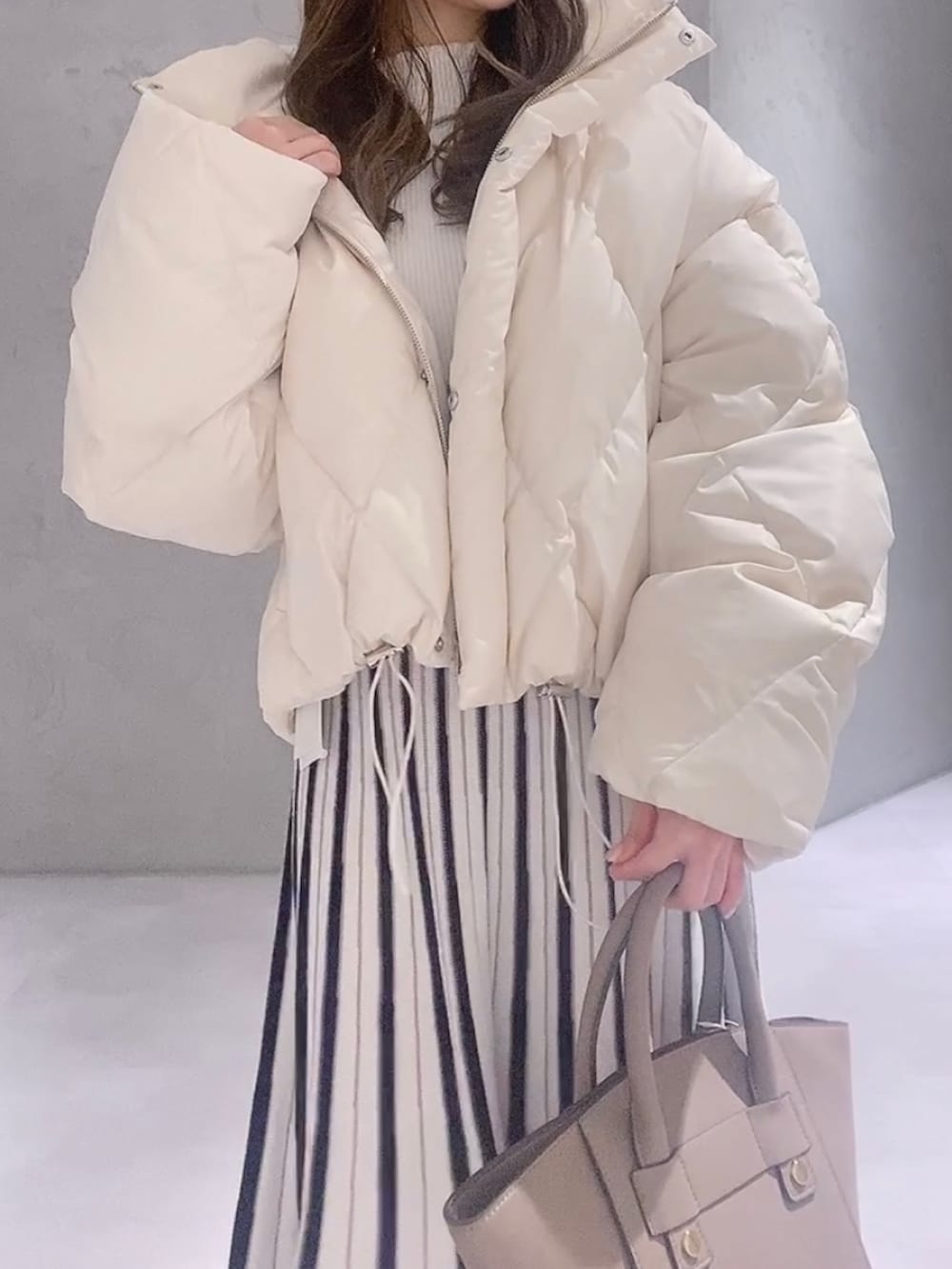 ホワイト系のワンピース、ホワイト系のブーツ、ブラウン系のハンドバッグを着用したレディースの冬コーディネートの3枚目の写真