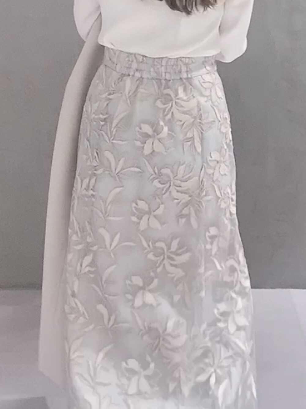 ホワイト系のニット/セーター、ホワイト系のチェスターコート、ブラウン系のハンドバッグを着用したレディースの冬コーディネートの7枚目の写真