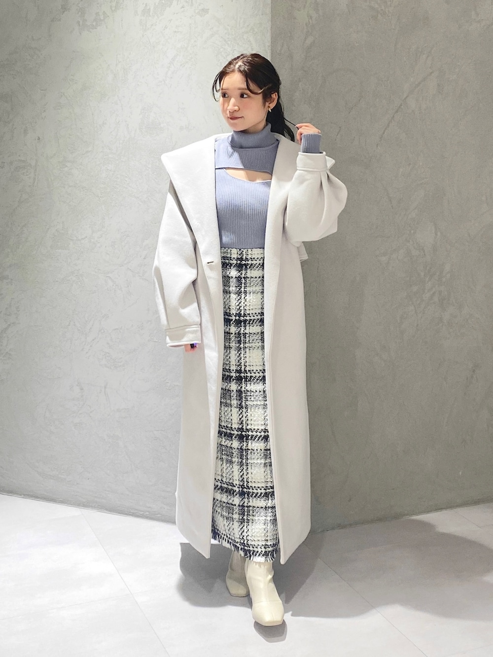 ホワイト系のスカート、ブルー系のニット/セーター、ホワイト系のチェスターコートを着用したレディースの冬コーディネートの3枚目の写真