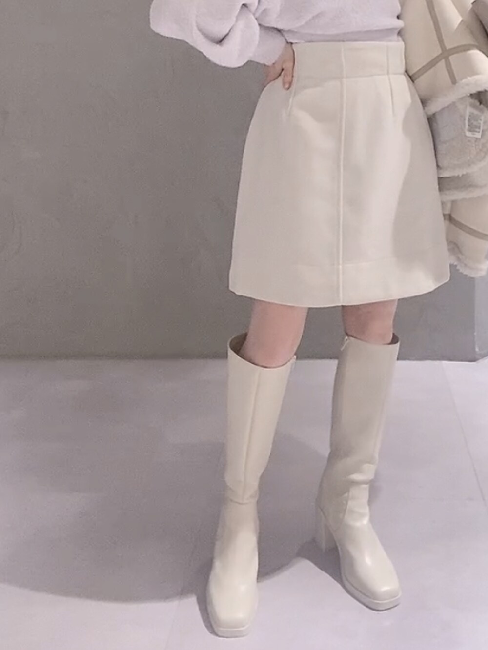 ベージュ系のハンドバッグ、ホワイト系のムートンコート、パープル系のニット/セーターを着用したレディースの冬コーディネートの7枚目の写真