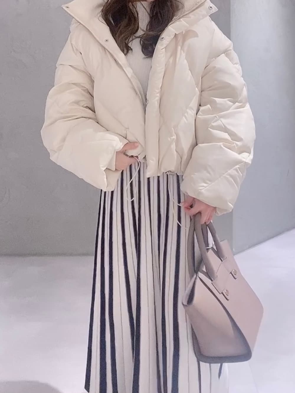 ホワイト系のワンピース、ホワイト系のブーツ、ブラウン系のハンドバッグを着用したレディースの冬コーディネートの2枚目の写真