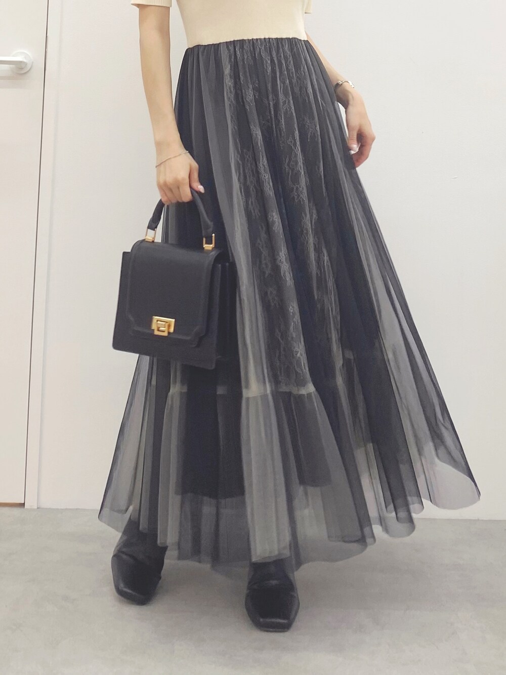 ブラック系のハンドバッグ、ブラック系のブーツ、ホワイト系のワンピースを着用したレディースの夏コーディネートの4枚目の写真